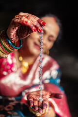 A traditional Indian woman is showcasing her beautiful silver anklet by holding it in her hand.