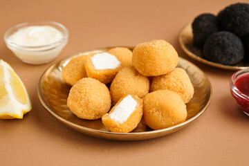 Plate with delicious fried mozzarella balls and lemon piece on beige background