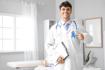 Fototapeta premium Male doctor with blue ribbon and clipboard in clinic. Prostate cancer awareness concept