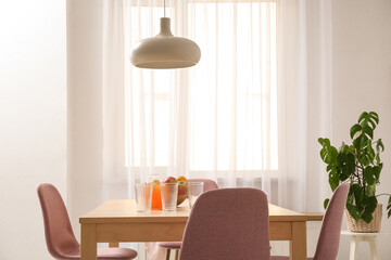 Table with fruits in bowl and jug of juice in interior of dining room