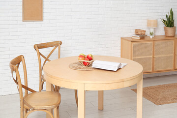 Table with apples and book in interior of dining room