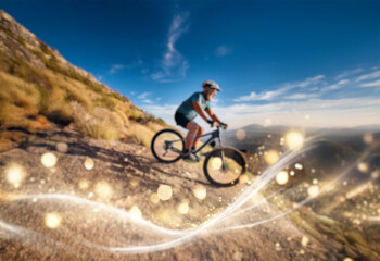 A mountain biker speeds down a rugged trail with sparkling light trails in the air.