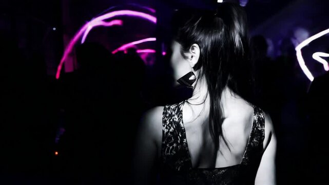 Mysterious woman in dark setting with glowing pink neon accent against black background