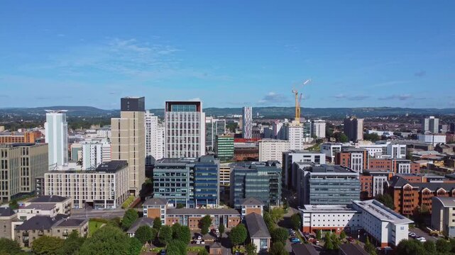 Aerial drone footage of Cardiff city centre as seen from Atlantic Wharf and Butetown neighbourhoods with modern apartment and office blocks in the foreground. Revealing straight pull-out shot.