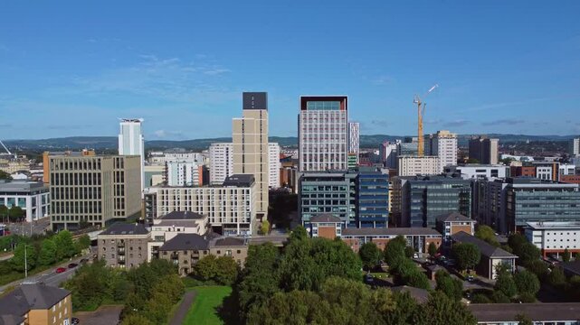 Aerial drone footage of Cardiff city centre as seen from Atlantic Wharf and Butetown neighbourhoods with modern apartment and office blocks in the foreground. Push in shot towards two buildings.