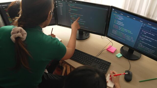 Slow motion back end software developer engineer for computer programming working together on debugging writing computing code, solving complex algorithms display on monitor in office. Burgeoning