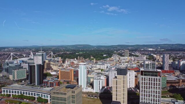 Aerial drone footage of Cardiff city centre as seen from Atlantic Wharf and Butetown neighbourhoods with modern apartment and office blocks in the foreground. Revealing pull-out shot with panning