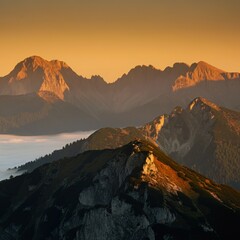 Naklejka premium Mist-covered mountain peaks with a golden sunrise in the distance
