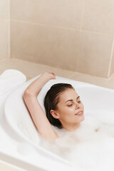 Naklejka premium Relaxed young woman enjoying a bubble bath in a luxurious bathtub, creating a serene atmosphere. Self-care and wellness concept for personal relaxation.