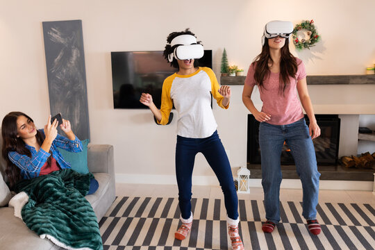 mutliracial female friends enjoying virtual reality gaming at home during Christmas celebration
