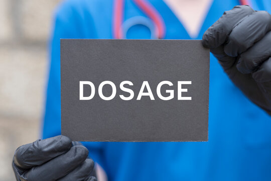 Doctor holding black card with word: DOSAGE. Daily dosage time medicine pharmaceutical concept. Dosage of medical drugs.