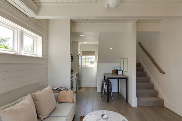 The cozy Oregon cottage features a welcoming sectional, perfect for relaxation. A charming staircase leads to an upper level, while a dedicated work area showcases modern functionality.