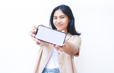 excited asian woman showing smartphone blank screen hold on hands to camera wearing casual brown clothes and jeans isolated on white background