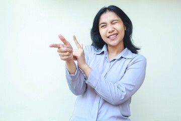 image of smiling beautiful young business woman manager pointing finger and blink eye excited to introduce product, wear formal shirt, isolated over white background