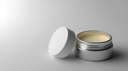 small,open metal container shows a pale creamy substance inside,placed neatly on a light surface with gentle illumination,emphasizing its texture,copy space
