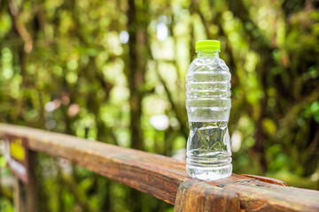 Water bottle on wooden table on blurred green nature background