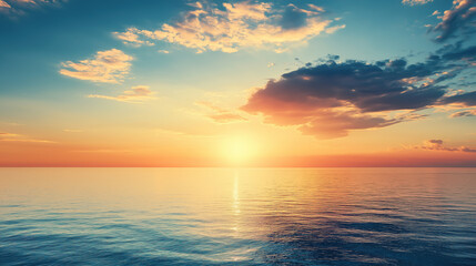 Fototapeta premium A beautiful sunset over the calm sea, with clouds in the sky and warm colors reflecting on the water's surface