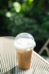 Strong coffee in a take-home cup sits on a vintage iron table in the garden...