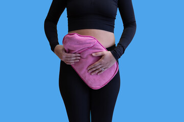 Female holding hot watter bottel to belly and keeping warm. This is easing her lower abodminal pain...