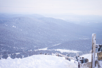 wooded snowy hills, wooden fence in foreground