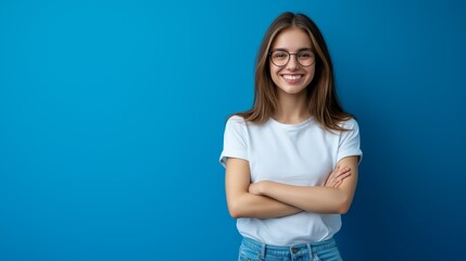 Obraz premium A young american smiling woman stands with her arms crossed against a blue background