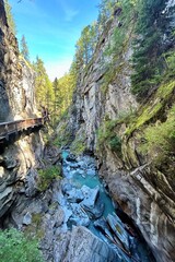 Alpine river running through rocky canyon valley and gorge with wooden cliff walk at Gorner Gorge in Zermatt, Switzerland