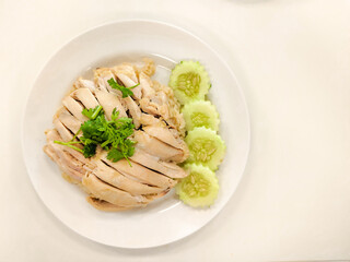 Steamed rice topped with chicken and slice cucumber on white the dish. Thai delicious street food. High protein nutrition.