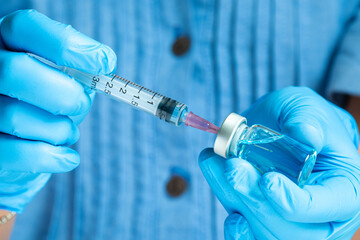 doctor's hand holds a syringe and a blue vaccine bottle at the hospital. Health and medical...
