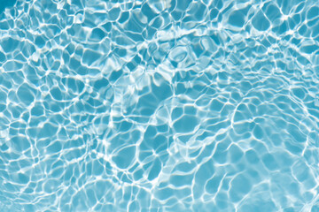 Blue water with ripples on the surface. Defocus blurred transparent blue colored clear calm water surface texture with splashes and bubbles. Water waves with shining pattern texture background.