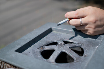 喫煙者の手と火のついたタバコと灰皿