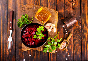 Plate of cut boiled beets with parsley on wooden table