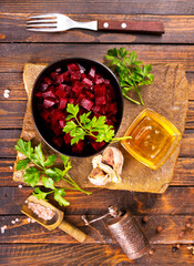 Plate of cut boiled beets with parsley on wooden table
