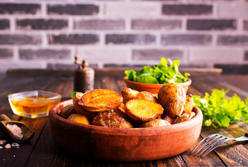 baked potato wedges with spices and rosemary on a wooden background