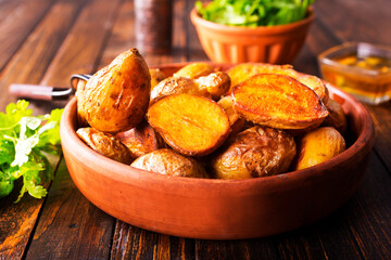 baked potato wedges with spices and rosemary on a wooden background