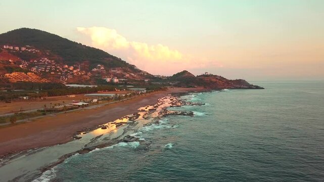 Aerial Drone Flyover Along Koru Beach in Gazipasa, Turkey, Capturing the Shoreline and Gentle Waves in Soft Sunset Light, Serene Coastal Scene with Tranquil Sea