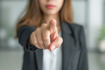 A professional woman in a suit points at the viewer, conveying a sense of success and agreement in a business setting