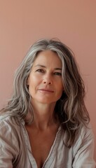 Fototapeta premium Serene Middle-Aged Woman Portrait on Pastel Pink Background for Relaxation Concepts