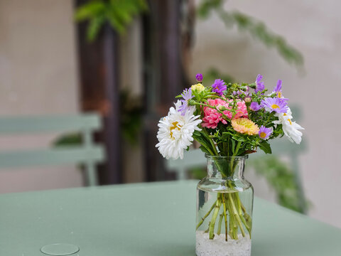 Beautiful mixed type of flowers in the transparent vase on the green dining table