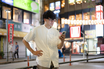 街でスマートフォンを操作する男性