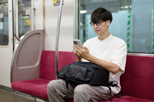 電車に乗る男性　スマホ　音楽