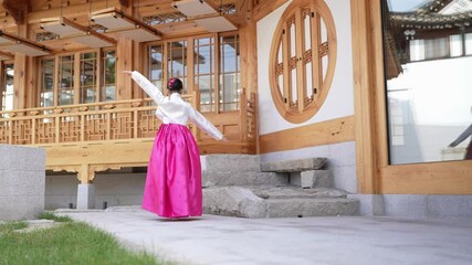 A 9-year-old Korean girl happily dances a traditional Korean dance in front of a historical building in Seoul, South Korea.
