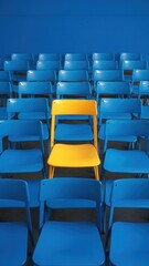 Obraz premium Yellow chair is sitting in a row of blue chairs