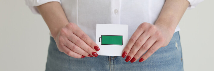 Woman in jeans and white shirt holds charged cell picture