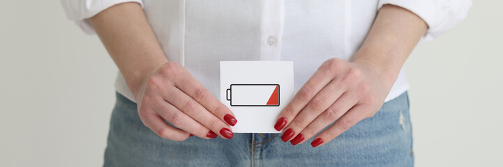 Woman in jeans and shirt shows discharged battery cell image