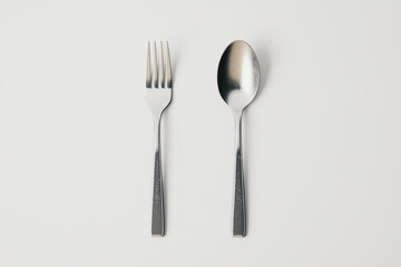 A sleek silver fork and spoon placed side by side on a pristine white surface, metallic reflections