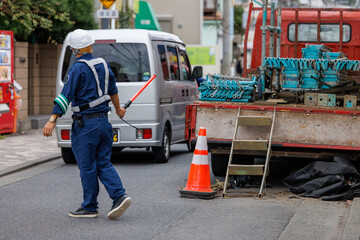 工事現場近くを走る自動車を誘導する交通誘導員