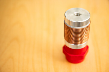 Electrotechnical coil made of copper wire for high frequency on a red insulator