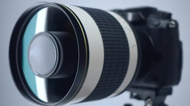 A professional camera on a tripod with a powerful mirror zoom lens that reflects the rotate light. Closeup. Macro