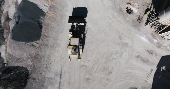 Stone crusher plant, loader transporting gravel, aerial top view.