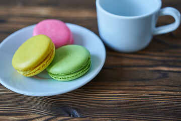 Colorful macaroons on a white plate on a wooden background